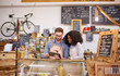 © marvent - Two smiling baristas using a tablet behind a cafe counter
