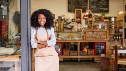 smiling african american barista standing welcomingly at a cafe door