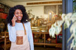 © marvent - Young African American cafe barista talking on her cellphone