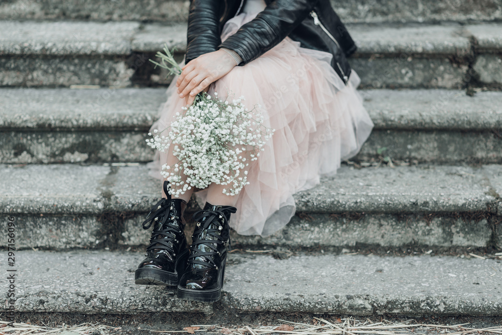 Woman in pink lace skirt with white flowers bouquet in her hands is sitting on stairs. - obrazy, fototapety, plakaty 