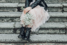 Woman In Pink Lace Skirt With White Flowers Bouquet In Her Hands Is Sitting On Stairs.