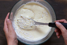 Top View Of Woman Hand Mixing With Whisk Dry Ingredients And Batter On Wooden Background