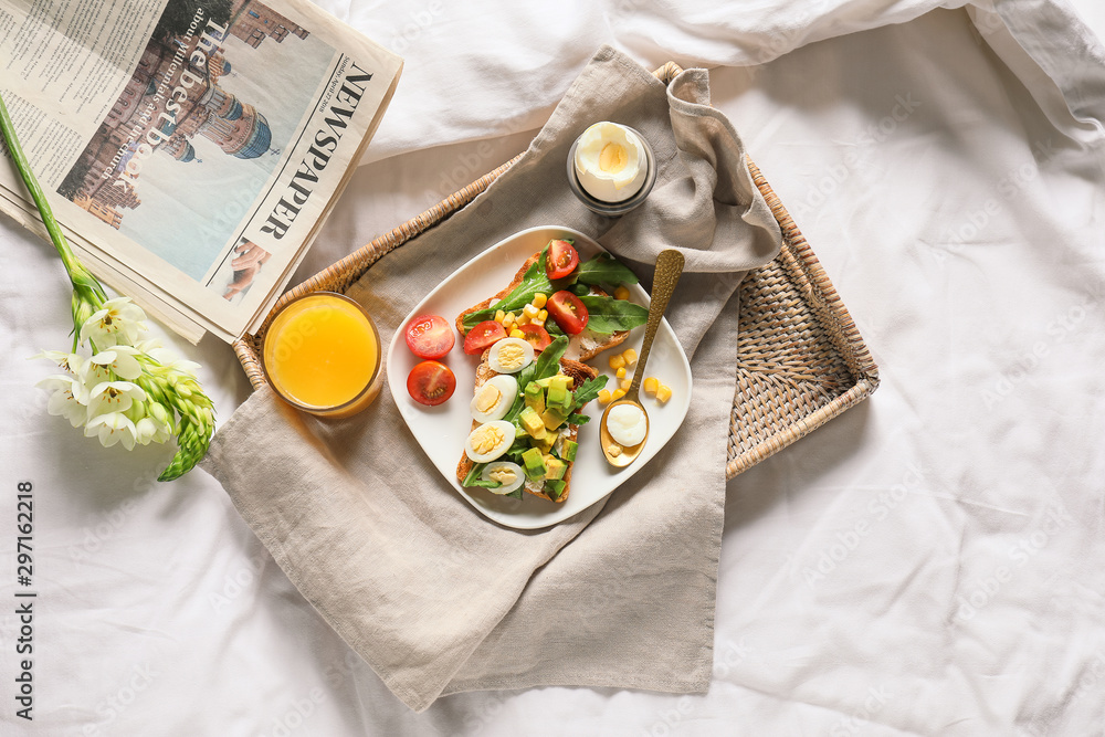 Tray with tasty sandwiches and juice on bed