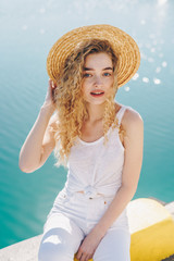 Wall Mural - romantic curly blonde in a hat against the sparkling sea