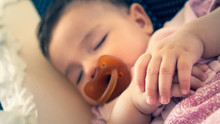 Hands Of Sleeping Baby With Pacifier In His Mouth In The Crib