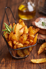 Potato wedges baked with rosemary. Delicious snack served with sauce. Fast food.