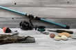 Fishing rod and other fishing tools and tools. There is a white wooden background.