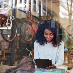 Wall Mural - Young African American woman in a cafe using a tablet