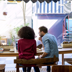 Wall Mural - Diverse young couple using their laptop together in a cafe