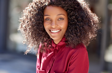 Wall Mural - Smiling young African American woman standing on a city sidewalk