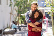 © marvent - Diverse young couple hugging while standing together on a sidewalk