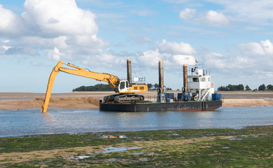 Wall Mural - Excavator on a barge digging out a coastal channel