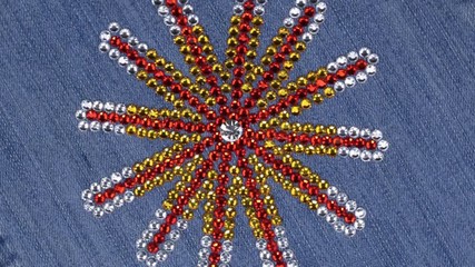 Wall Mural - Rotation of multi-colored rhinestones laid out in the shape of a star on denim.