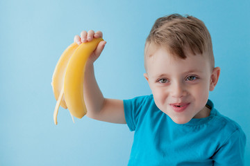 Wall Mural - Little Boy Holding and eating an Banana on blue background, food, diet and healthy eating concept