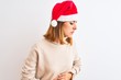 © Krakenimages.com - Beautiful redhead woman wearing christmas hat over isolated background with hand on stomach because indigestion, painful illness feeling unwell. Ache concept.