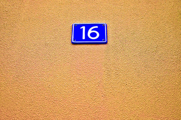 16, number sixteen, blue plate on pale orange surface.