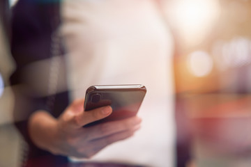 Close-up of woman using smartphone with typing an sms message to friends and walking in mall.