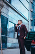© qunica.com - Entrepreneur(Businessman) standing in an urban area and wearing a suit and tie next to his limo while talking on the phone.