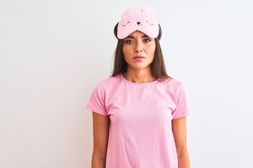 Poster - Young beautiful woman wearing sleep mask standing over isolated white background with serious expression on face. Simple and natural looking at the camera.