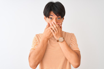 Wall Mural - Young chinese man wearing casual striped t-shirt standing over isolated white background shocked covering mouth with hands for mistake. Secret concept.