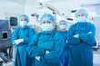 © DragonImages - Smiling Vietnamese female chief surgeon standing in front of her team, folding arms and looking at camera