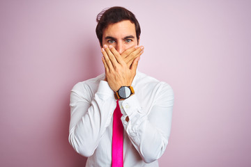 Poster - Young handsome businessman wearing shirt and tie standing over isolated pink background shocked covering mouth with hands for mistake. Secret concept.