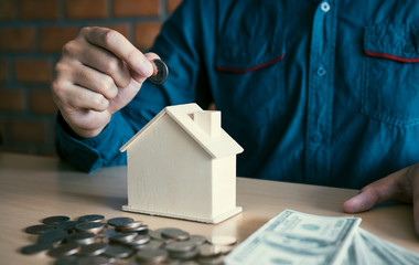 Wall Mural - Men are putting coins together with the idea of collecting money to buy a new house.