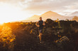 Young male athlete trail running in mountains at sunrise. Amazing black lava volcanic landscape of Bali on background. Adventure sport concept.