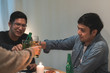 © tirachard - Merry Christmas and Happy New Year! Young friends group having dinner at home. Asian family party with beer and pizza food near christmas tree at house in night. Celebration holiday and togetherness.