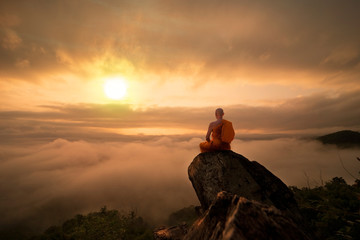 Wall Mural - Buddhist monk in meditation at beautiful sunset or sunrise background on high mountain