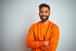 © Krakenimages.com - Young indian man wearing orange sweater over isolated white background happy face smiling with crossed arms looking at the camera. Positive person.