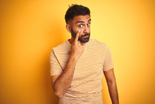 Young Indian Man Wearing T-shirt Standing Over Isolated Yellow Background Pointing To The Eye Watching You Gesture, Suspicious Expression