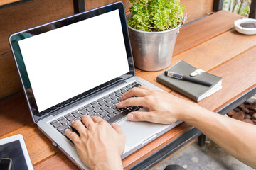 man using laptop computer with blank screen on wooden table