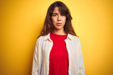 Wall Mural - Young beautiful woman wearing red t-shirt and stripes shirt over yellow isolated background depressed and worry for distress, crying angry and afraid. Sad expression.