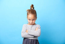 Offended Little Girl Crosses Her Arms And Makes A Disgruntled Expression Of Protest. Naughty Child On Blue Isolated.