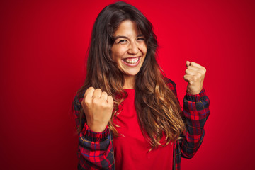 Wall Mural - Young beautiful woman wearing casual jacket standing over red isolated background smiling and looking at the camera pointing with two hands and fingers to the side.