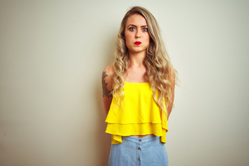 Sticker - Young beautiful woman wearing yellow t-shirt standing over white isolated background puffing cheeks with funny face. Mouth inflated with air, crazy expression.