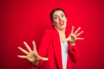 Canvas Print - Young beautiful business woman standing over red isolated background afraid and terrified with fear expression stop gesture with hands, shouting in shock. Panic concept.