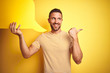 © Krakenimages.com - Young man holding empty speech bubble for message over yellow isolated background pointing and showing with thumb up to the side with happy face smiling