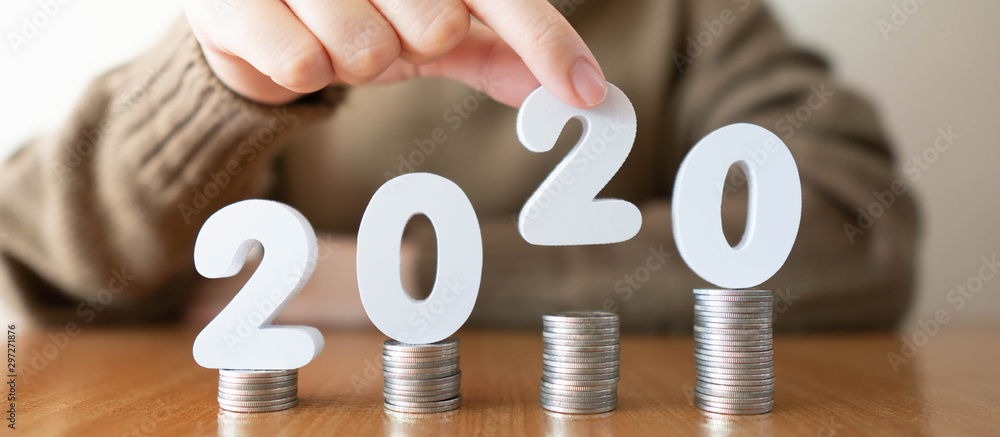 2020 New year saving money and financial planning concept. Female hands putting white number 2020 on stack of coins. Creative idea for business growth, tax payment, investment and banking. - obrazy, fototapety, plakaty 