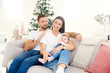 © gzorgz - Lovely family with their baby girl relaxing on sofa at home during Christmas