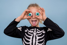 Little Boy In Skeleton Costume Holding Scary Toy Eyeballs Over His Eyelids