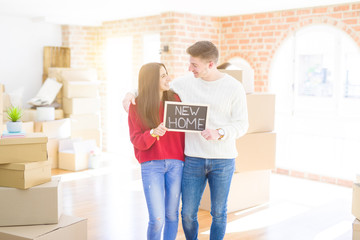 Poster - Beautiful young couple hugging in love and holding blackboard moving to a new home, smiling happy for new apartment