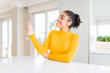 Sticker - Beautiful african american woman with afro hair wearing a casual yellow sweater Looking proud, smiling doing thumbs up gesture to the side