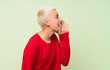 © luismolinero - Teenager girl with white short hair over green wall shouting with mouth wide open to the lateral