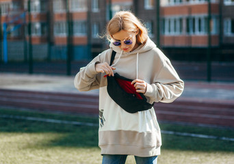 Sticker - Stylish model girl at the city in a grey hoodie and glasses with waist bag