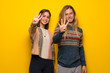 © luismolinero - Hippie couple over yellow background happy and counting four with fingers