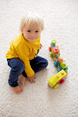 Wall Mural - Cute toddler boy, playing with wooden train and teddy bear on isolated background