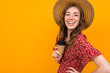 © Ivan Traimak - cheerful european woman laughs on an orange background, a girl in a hat and a red dress with coffee in hand