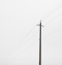 The Electric Pole And Wires In Front Of Gray Foggy Cloud. Concept Of Minimalist Photo